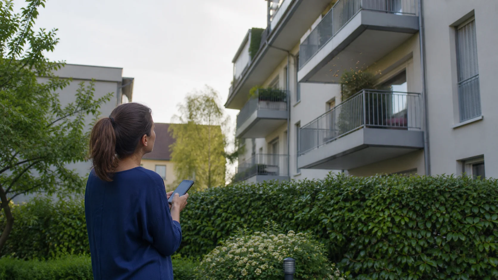 Une résidente observe à distance un va-et-vient d’insectes près d’un balcon, sans se rapprocher du point d’entrée.